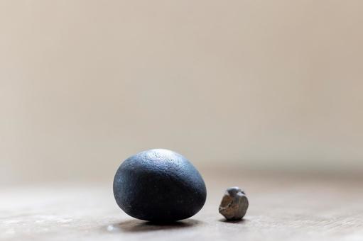 シンプルな大小２つの石ころ｜テーブル上 石,丸石,黒の写真素材