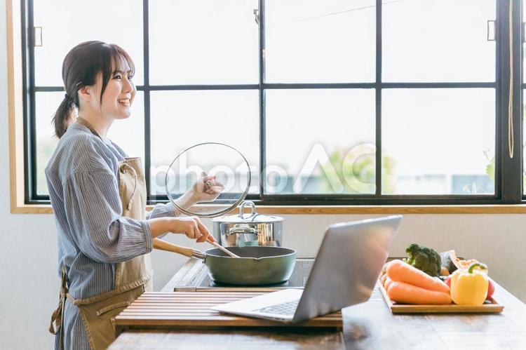 パソコンでレシピを見ながら料理をする女性 料理,パソコン,レシピ動画の写真素材