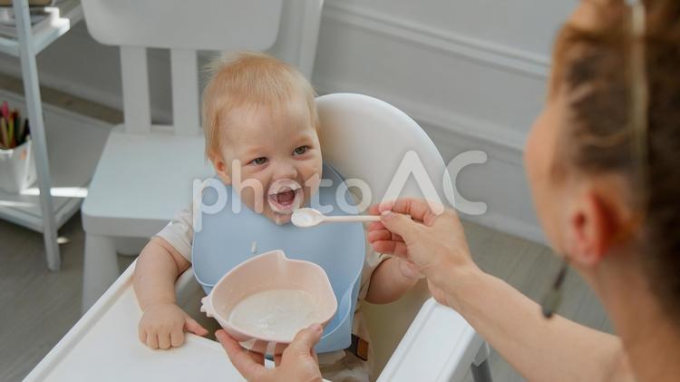 口を開ける赤ちゃんと食べさせる女性 女性,赤ちゃん,人物の写真素材
