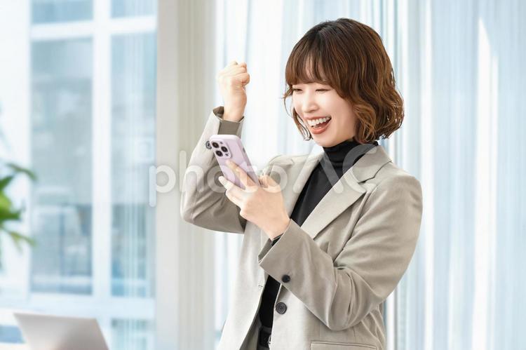 スマホを見て喜ぶ女性・ビジネスウーマン 女性,スマホ,スマートフォンの写真素材