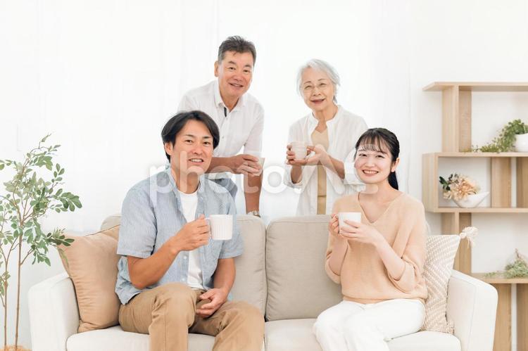 ソファに座って飲み物を飲む家族（カメラ目線） 家族,親子,お茶の写真素材
