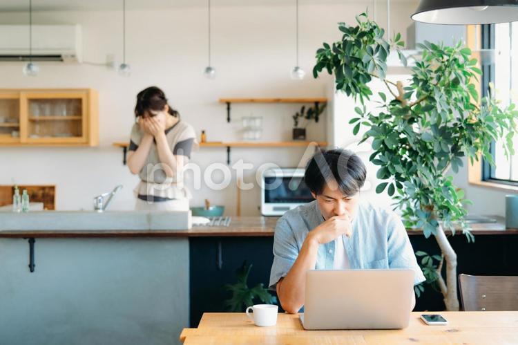 辛い思いをする女性とパソコンを使う男性 夫婦,離婚,ストレスの写真素材