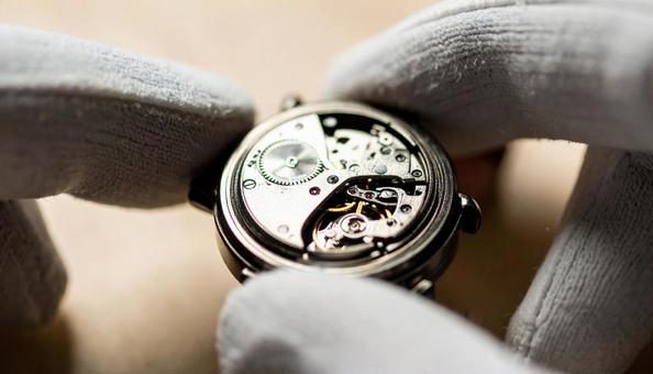 手袋で高級時計を持って鑑定している鑑定士の写真