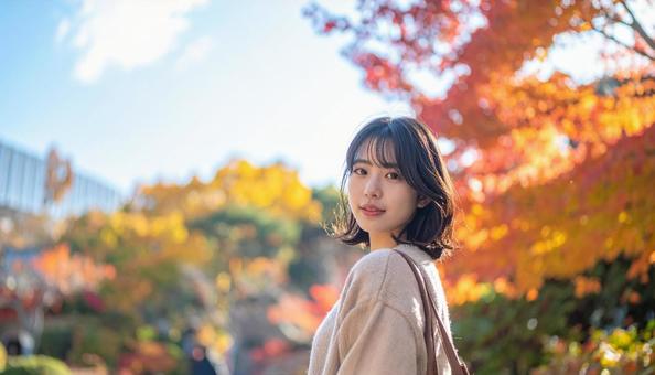 紅葉を背景に笑顔で振り返る若い女性 紅葉を背景に笑顔で振り返る若い女性の写真