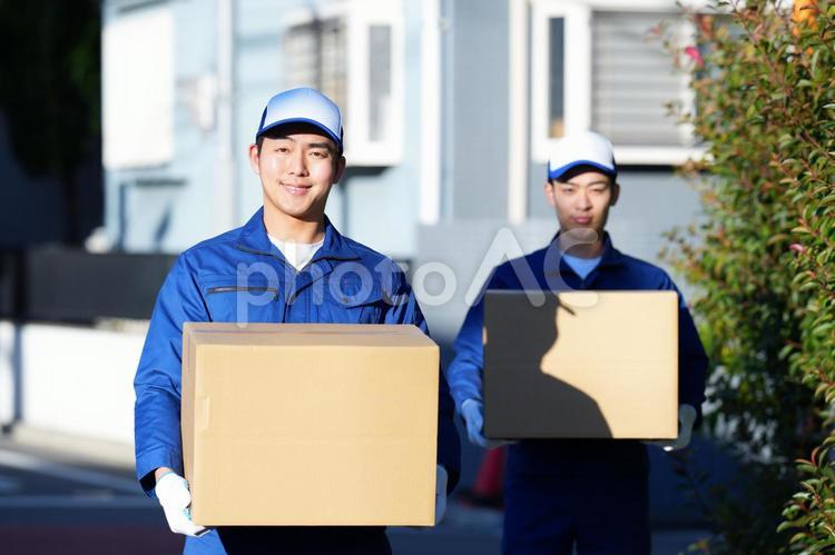 屋外で段ボール箱を持って立っている2人の引っ越し作業員 引っ越し,男性,日本人の写真素材