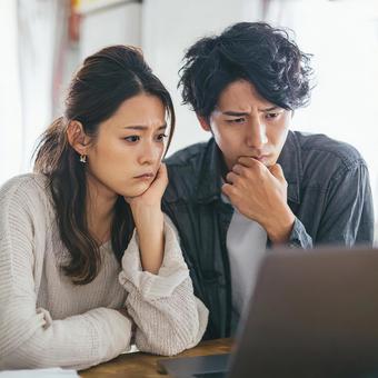 リビングでパソコンを見る男女 リビングでパソコンを見る男女の写真