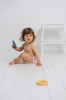 玩具を持ち振り向くオムツの赤ちゃん 赤ちゃん,かわいい,お座りの写真素材