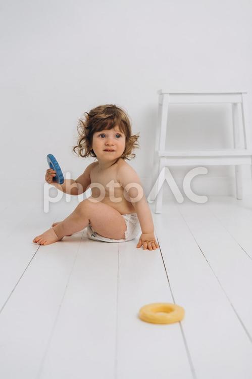 玩具を持ち振り向くオムツの赤ちゃん 赤ちゃん,かわいい,お座りの写真素材