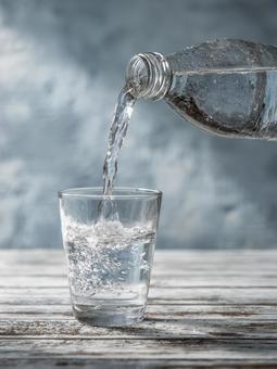 ペットボトルからコップへ水を注ぐ ペットボトルからコップへ水を注ぐの写真