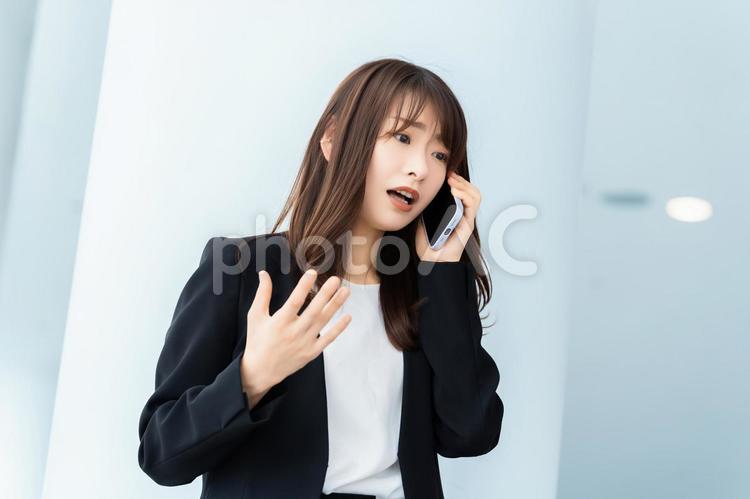 スマホで話す困った表情の女性 女性,スマホ,スマートフォンの写真素材