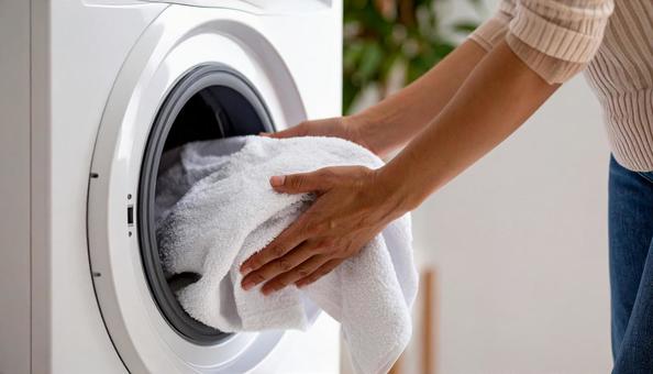 洗濯機から洗濯物を取り出す女性の手 洗濯機から洗濯物を取り出す女性の手の写真