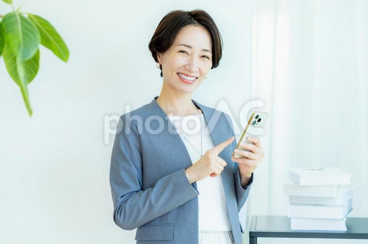 スマホを操作するビジネスウーマン スマホ,笑顔,ミドルの写真素材