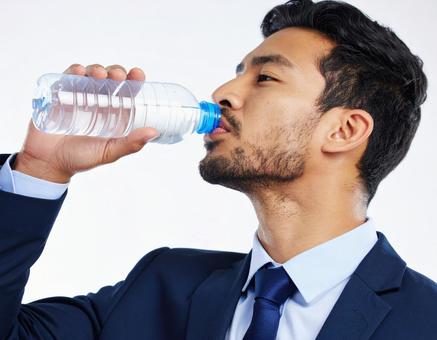 ペットボトルの水を飲むビジネスマン ペットボトルの水を飲むビジネスマンの写真