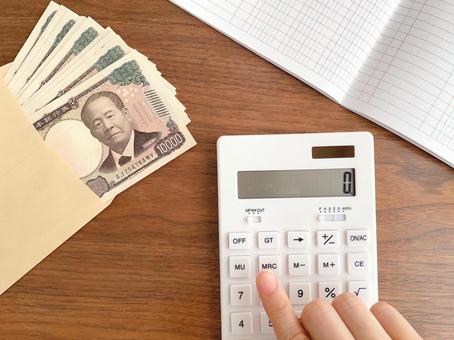 封筒に入った紙幣と電卓で計算する手元 封筒に入った紙幣と電卓で計算する手元 電卓,計算,お金の写真素材
