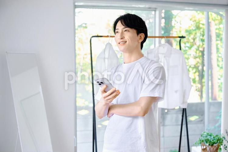 スマホを持つ男性　朝の身支度　準備 男性,スマホ,身支度の写真素材