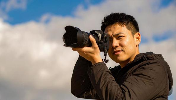 レンズを向ける日本人男性カメラマンの写真