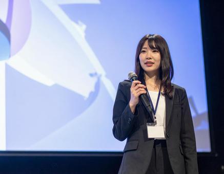スクリーンの前でプレゼンする女性 スクリーンの前でプレゼンする女性の写真