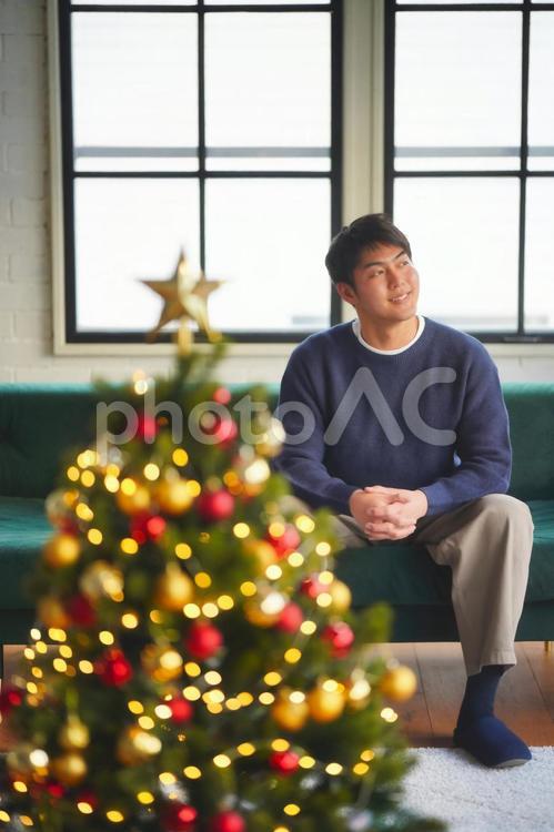 座ってよそ見する男性とクリスマスツリー 男性,リビング,ソファーの写真素材