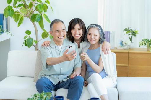 リビングでスマホを見るシニア夫婦と子供 シニア,夫婦,スマホの写真素材
