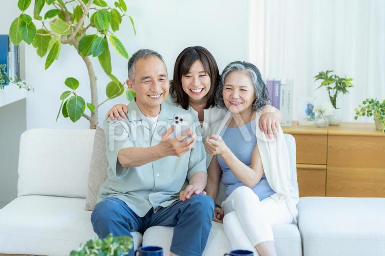 リビングでスマホを見るシニア夫婦と子供 シニア,夫婦,スマホの写真素材