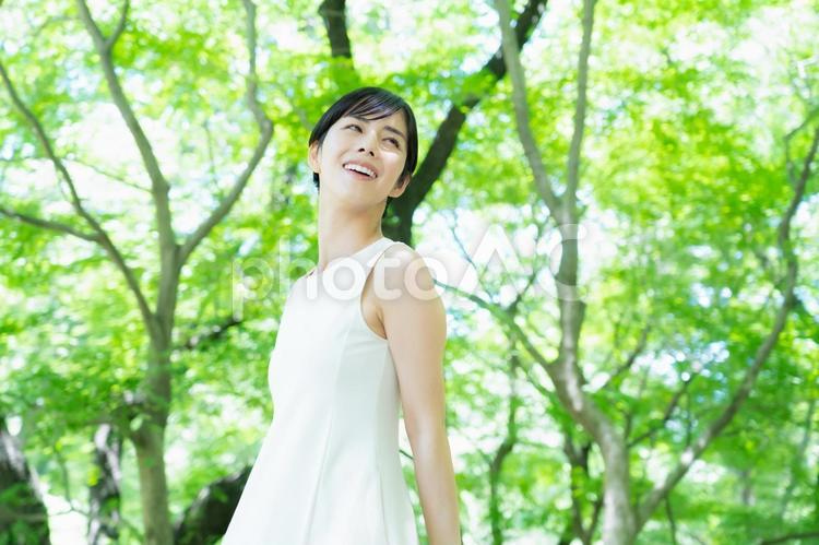 緑の中でスキンケアをする若い女性　 スキンケア,ビューティー,女性の写真素材