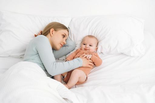 笑顔の赤ちゃんを見る真顔の女性 笑顔の赤ちゃんを見る真顔の女性 寝かしつけ,真顔,疲れたの写真素材