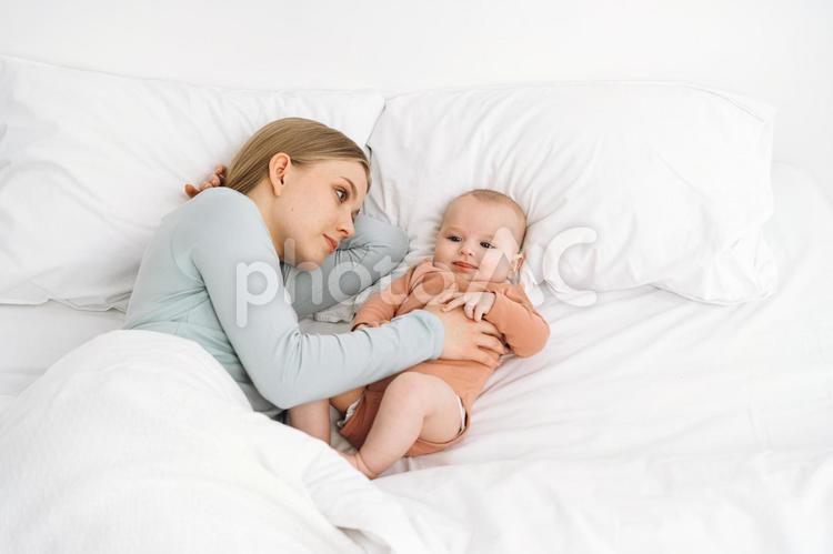 笑顔の赤ちゃんを見る真顔の女性 寝かしつけ,真顔,疲れたの写真素材