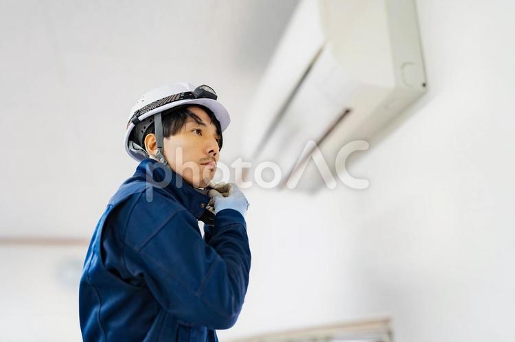 ヘルメットを外そうとする電気工事作業員 ヘルメットを外そうとする電気工事作業員 ビジネス,ビジネスマン,男の写真素材