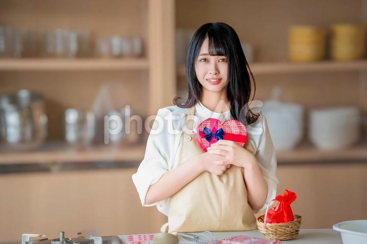ハートのチョコを持つエプロン姿の女性 バレンタイン,バレンタインデー,チョコの写真素材