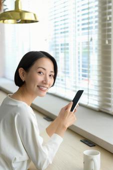 カフェでスマホを操作する日本人女性 カフェでスマホを操作する日本人女性の写真