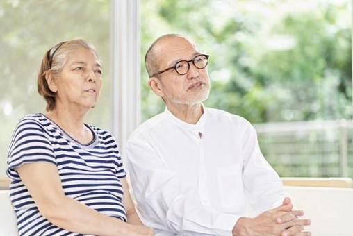 一對老夫婦坐在沙發上認真交談 一對老夫婦坐在沙發上認真交談