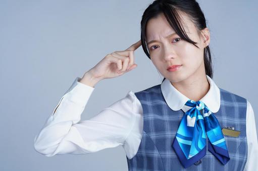 青いリボンの制服の女性がこめかみに手を当てて考える 女性,考える,困るの写真素材
