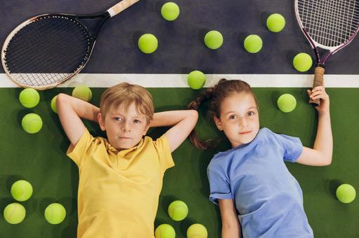ラケット横でくつろぐ男の子と女の子 男女,子供,外国人の写真素材
