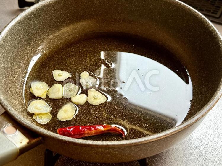 調理中のニンニクと唐辛子、オリーブオイル ニンニク,赤唐辛子,鷹の爪の写真素材