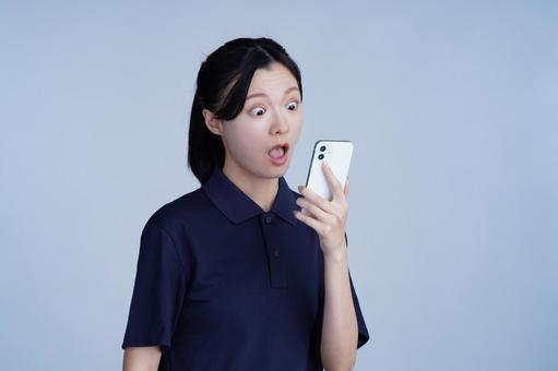 紺色の服の女性がスマホを見る 女性,スマートフォン,持つの写真素材