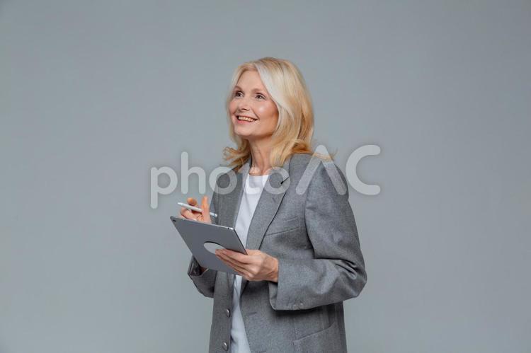 タブレットとペンと持って遠くを見ている女性 女性,ビジネスマン,遠くの写真素材