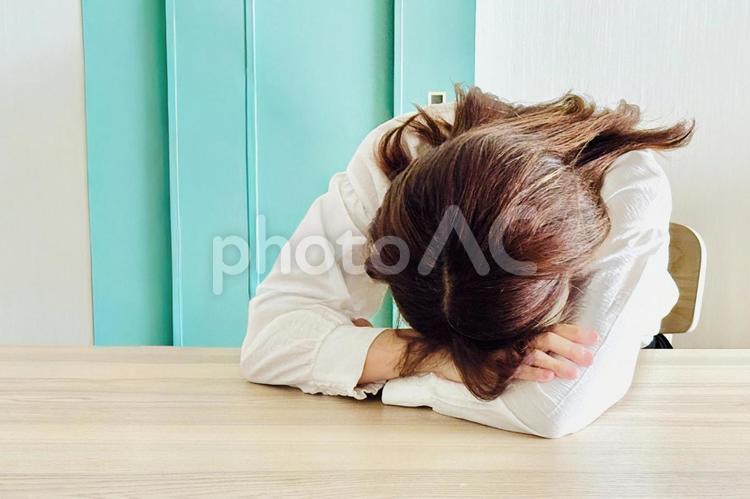 机に伏せている女性 女性,落ち込む,うつ伏せの写真素材