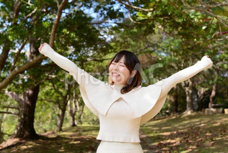 自然の中で両手をあげる笑顔の女性 女性,自然,笑顔の写真素材
