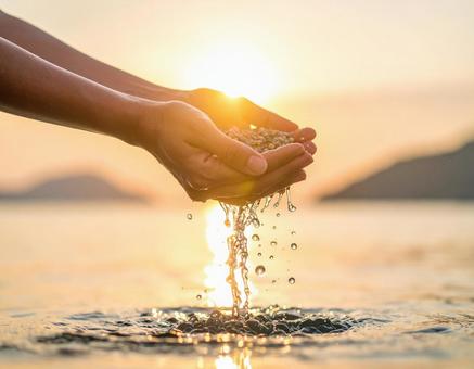 夕日と海水すくう女性の手 夕日と海水すくう女性の手の写真