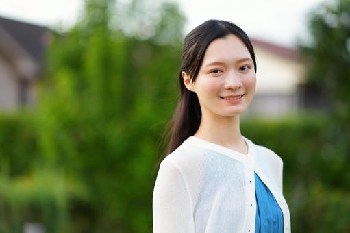 カメラ目線で微笑む白カーディガンの女性の写真