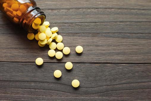 薬瓶からこぼれる黄色い錠剤 薬瓶からこぼれる黄色い錠剤 錠剤,薬,瓶の写真素材