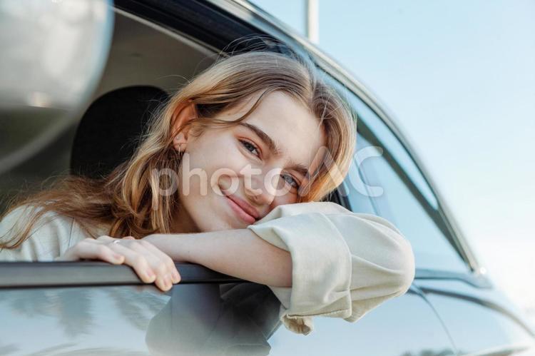 車から腕と顔を出して微笑む女性２ 女性,窓,顔出すの写真素材