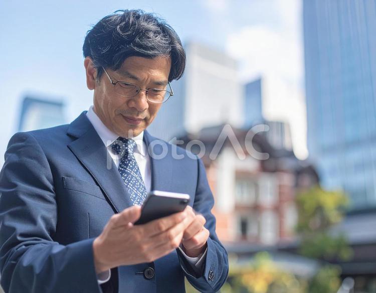 オフィス街でスマホを操作する男性社員 スマホ,ビジネス,操作の写真素材