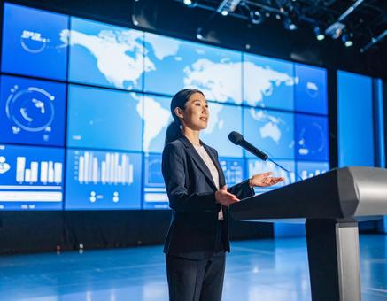 スクリーンの前でプレゼンする女性 スクリーンの前でプレゼンする女性の写真