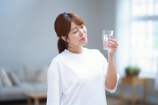 微笑み手に持った水のコップを見る女性 女性,水,飲み物の写真素材