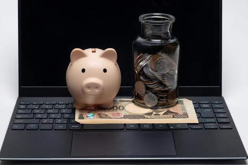 パソコンの上に置かれたお金と豚の貯金箱 パソコンの上に置かれたお金と豚の貯金箱 お金,パソコン,金融の写真素材