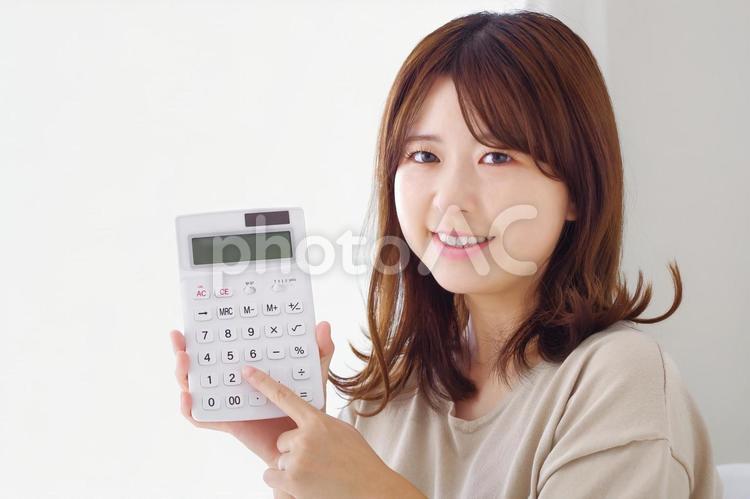 電卓を指さす笑顔の女性 電卓,計算,投資の写真素材