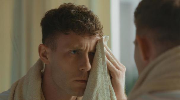 鏡を見ながら顔を拭く風呂上がりの男性 男性,外国人,欧米人の写真素材