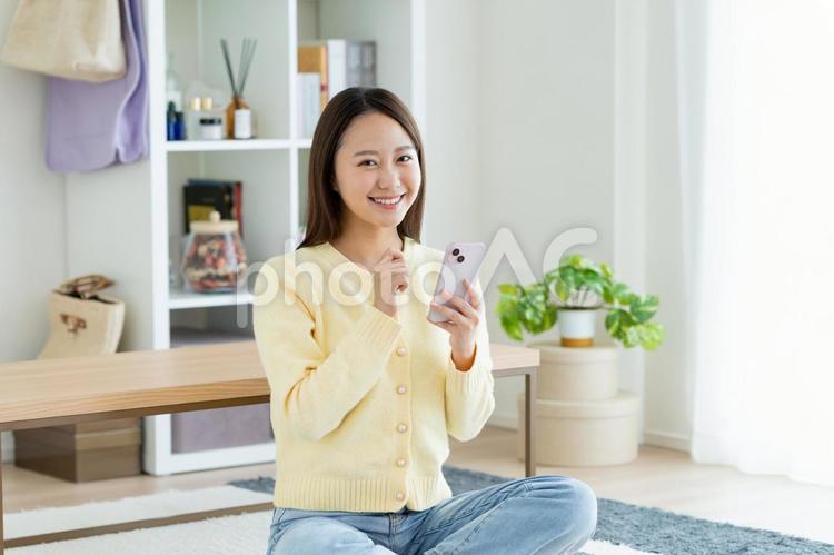 リビングでスマホを使う若い女性 リビングでスマホを使う若い女性 スマートフォン,女性,新生活の写真素材