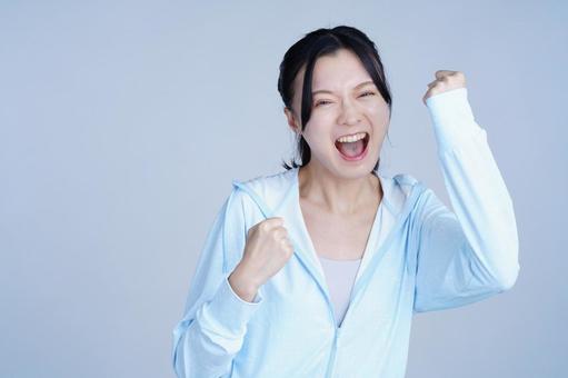 ガッツポーズをする水色の服の女性の写真